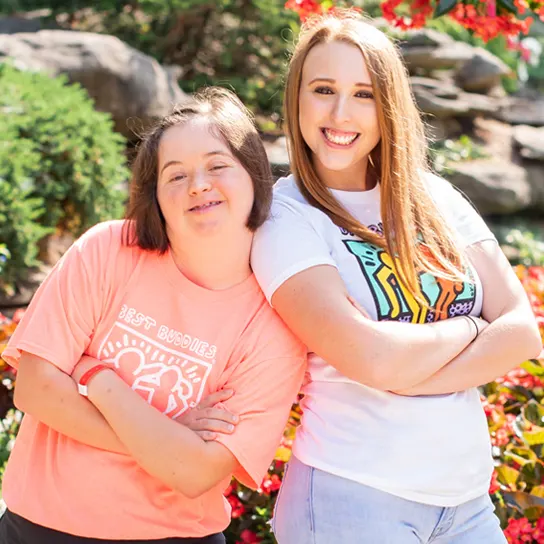 Two females Best Buddies participants standing back to back